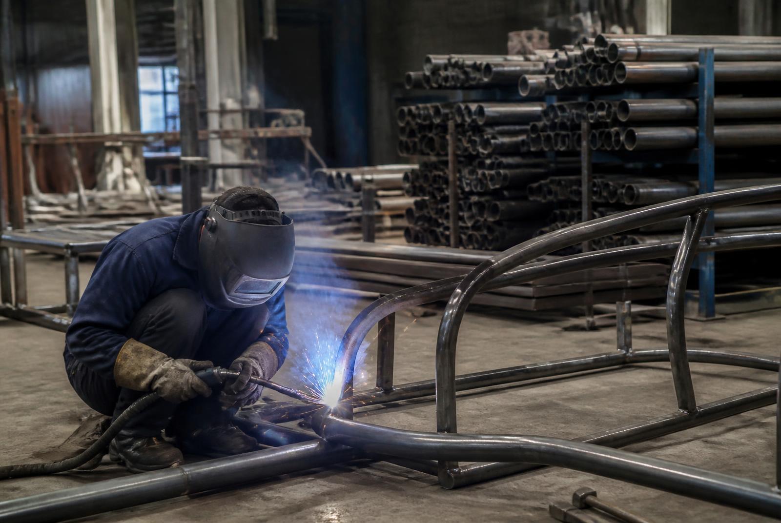 Welder fabricating steel frames on the ACHIEVER shop floor