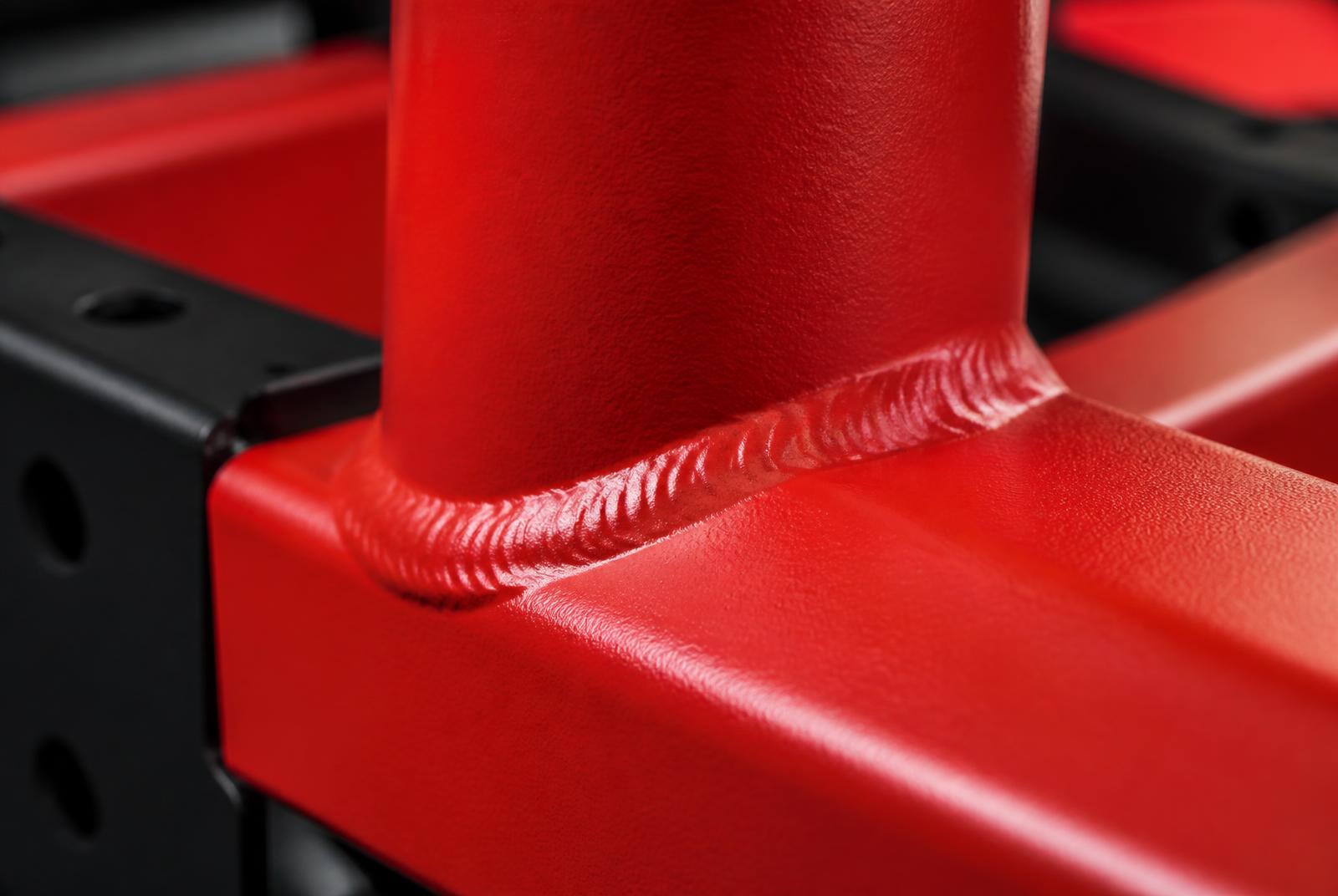 Close-up of a dressed weld on a red powder-coated steel frame